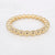 Gouden stainless steel bangle met glanzende ronde kralen in vaste vorm.