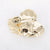 Gouden stainless steel broche met glanzende, organisch gevouwen vorm.
