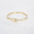 Gouden stainless steel bangle met vloeiende organische vorm en kliksluiting.