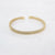Gouden stainless steel open armband met gevlochten textuur.